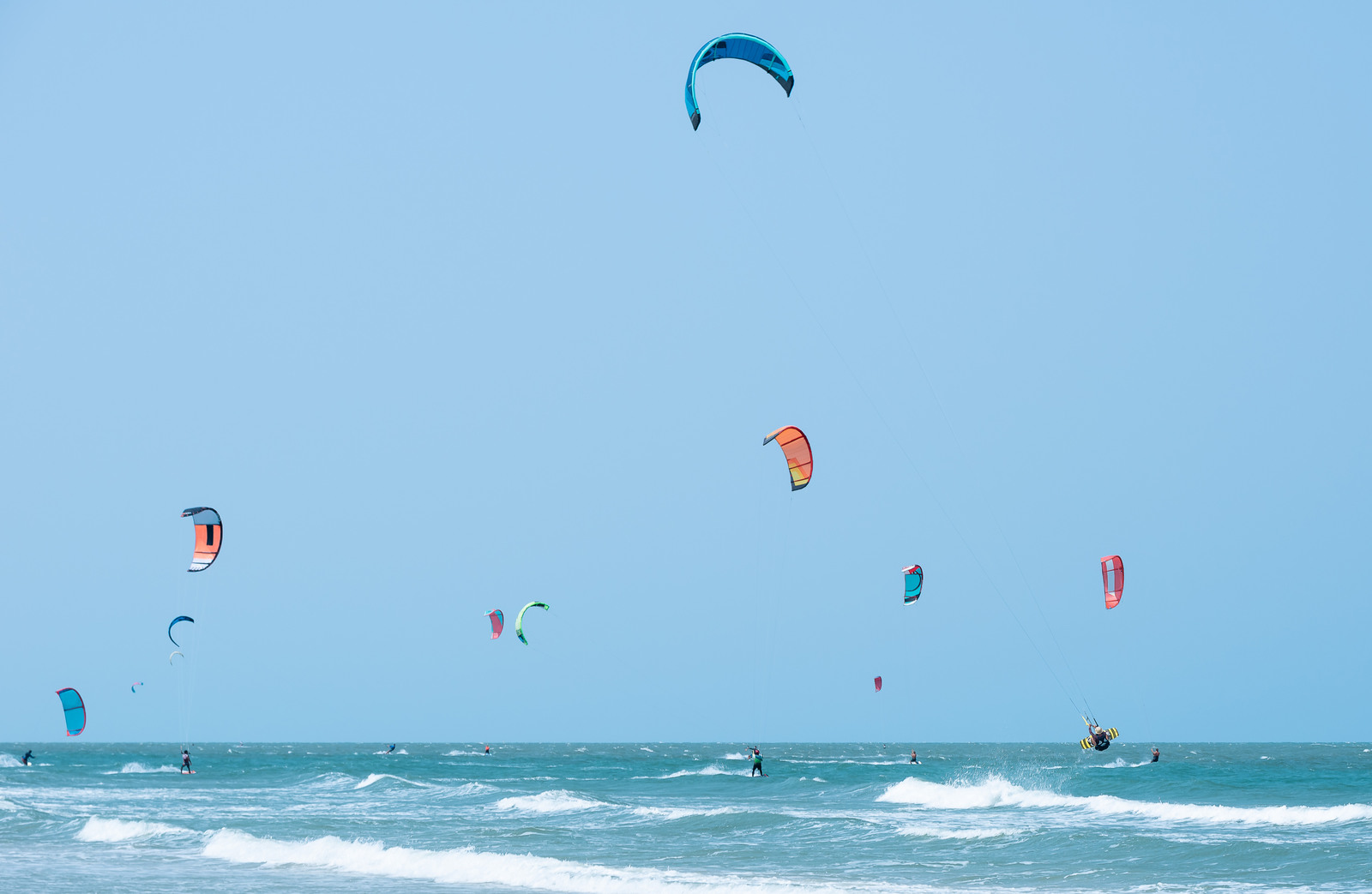 kitesurfers in Hua Hin line the sea as they catch waves on a windy day