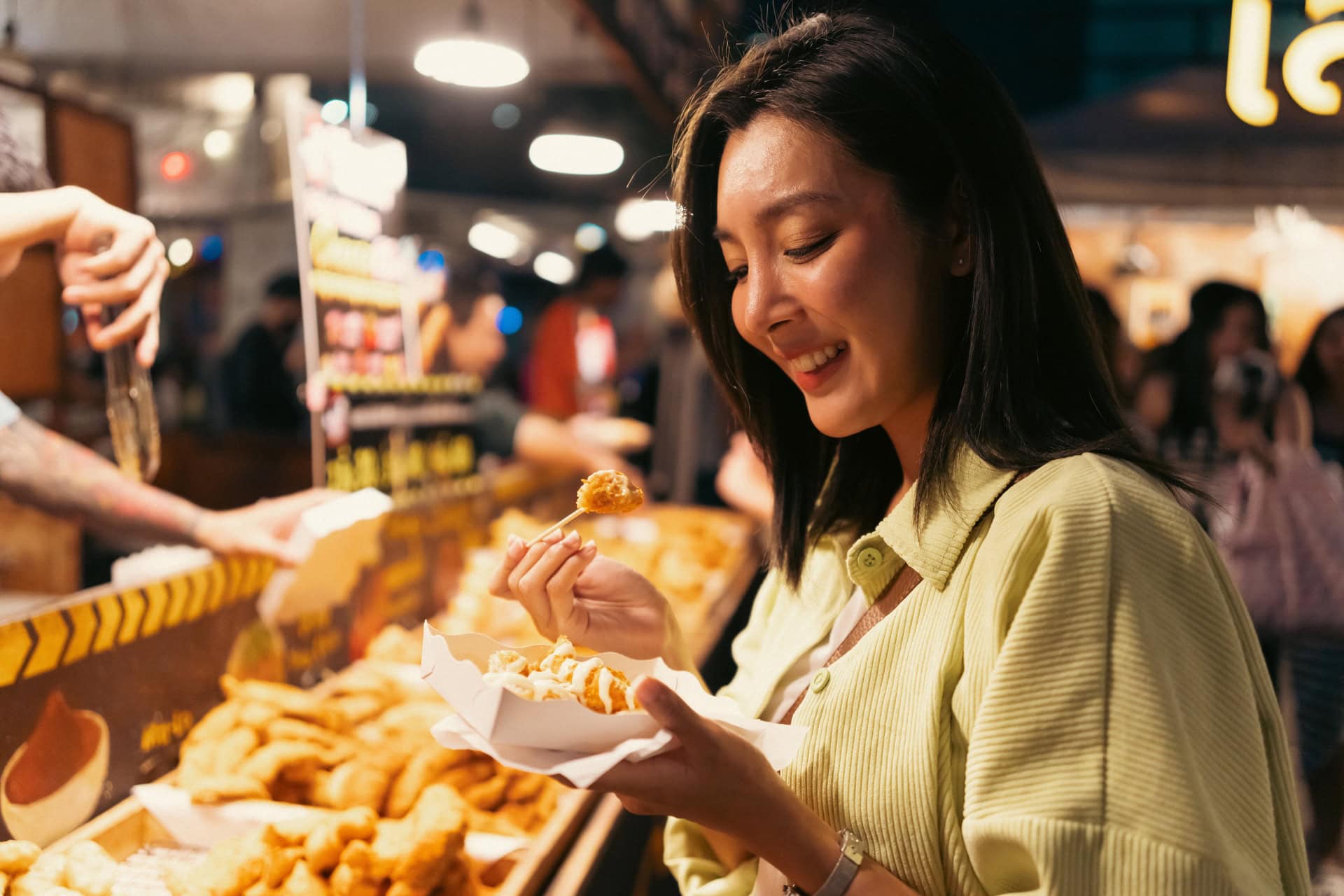A woman enjoying street food at Cicada Night Market